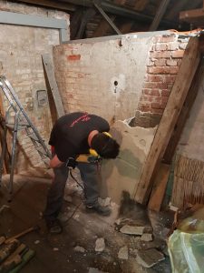 Einsatz des Schlagbohrers beim Entfernen des alten Kamins der Umluftheizung auf dem Dachboden der Stephanuskirche Nürnberg Gebersdorf