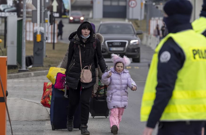 Frau mit Kind macht sich zu Fuß auf den Weg über die Grenze nach Polen. Sie hat einen großen Rollkoffer dabei.