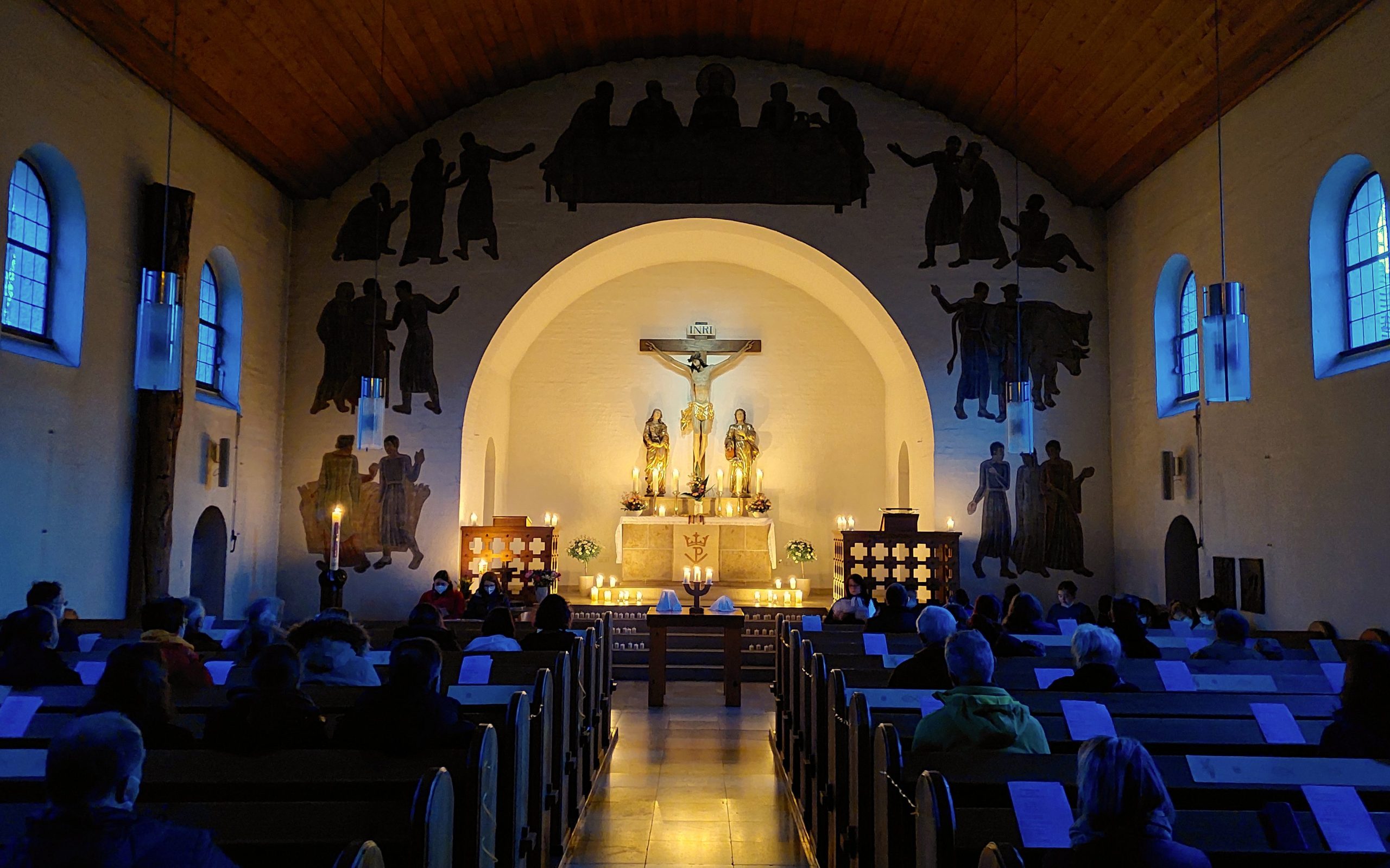 Osternacht in der Stephanuskirche. Der Altar ist durch Kerzenlicht hell erleuchtet, die Bankreihen sind noch im dunkeln.