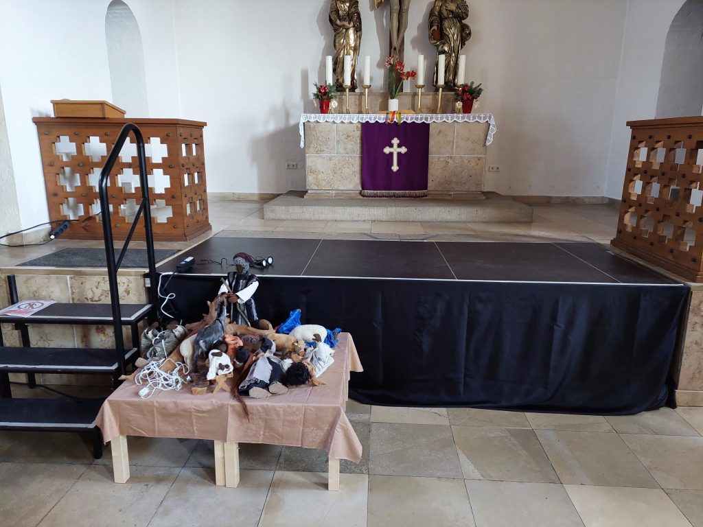 Bühne über den Altarstufen für die Familiengottesdienste. Davor die noch nicht aufgebauten Krippenfiguren auf einem Tisch.