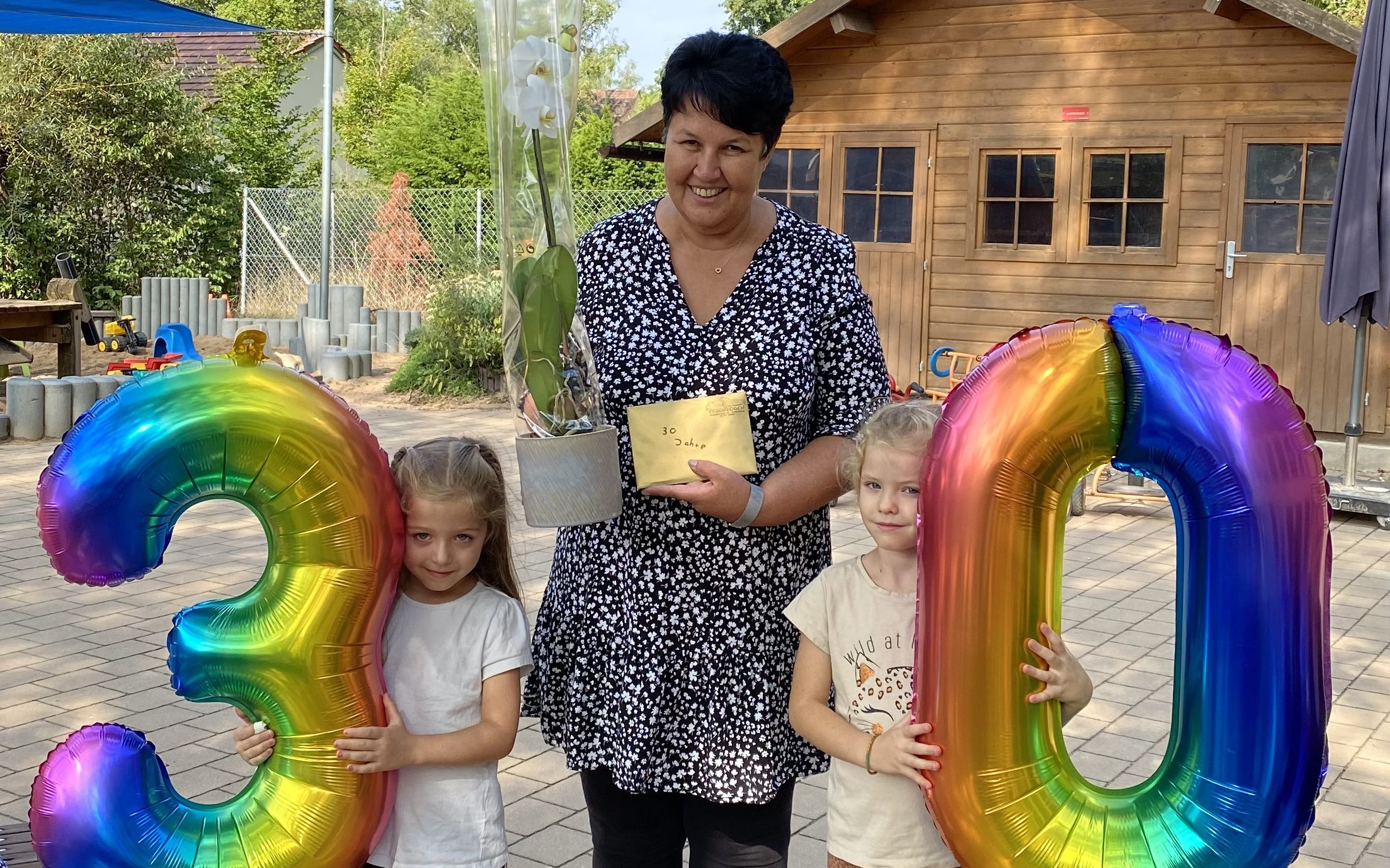 Inge Miess im Garten des Kindergartens Regenbogen mit den Geschenken zum Dienstjubiläum